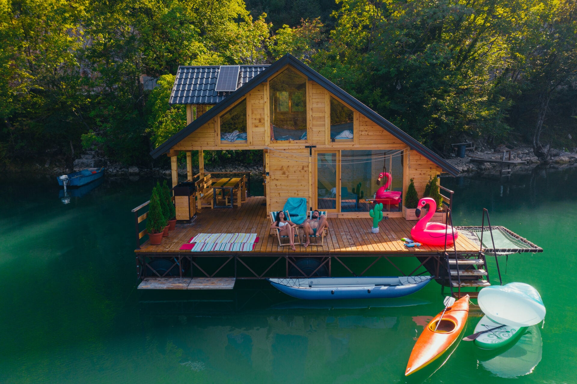 Couple relaxing at the weekend cottage with beautiful dock on the riverside. View from above