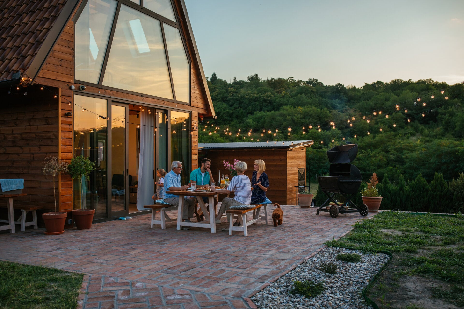 Three generation family having a garden party in the summer. They are sitting at the dining table in the backyard and having dinner
