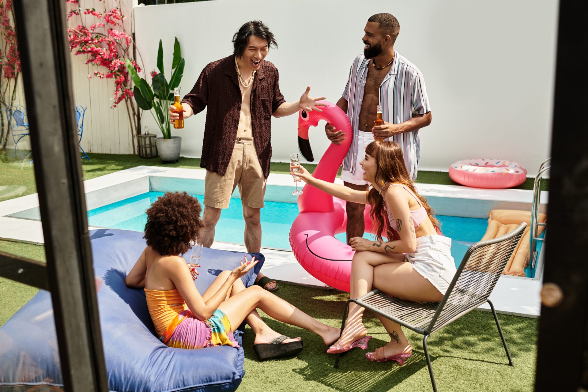 Young friends enjoy laughter and drinks while relaxing by the vibrant poolside area.