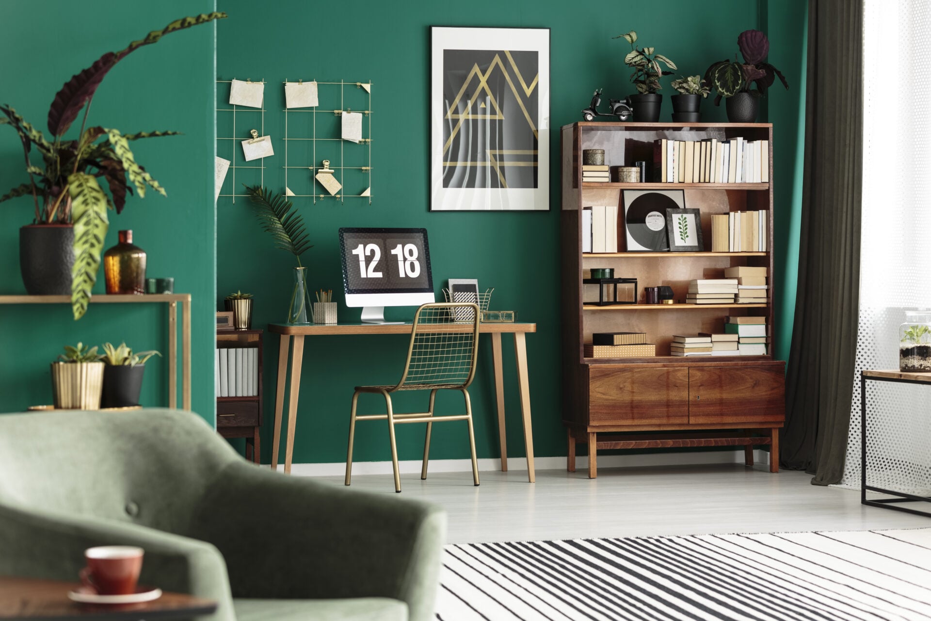 Gold chair at desk with desktop computer in green, cozy apartment interior with poster