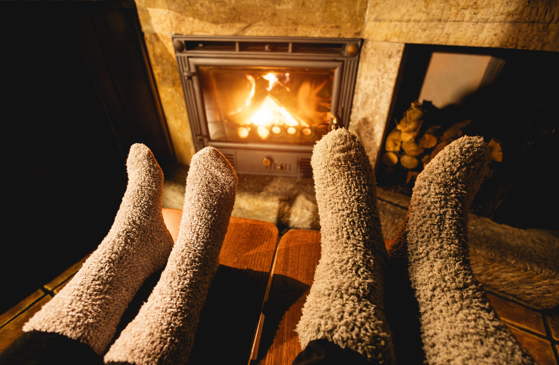 Legs view of couple wearing warm socks while resting in front of fireplace - Winter lifestyle and cozy concept - Main focus on right wool socks