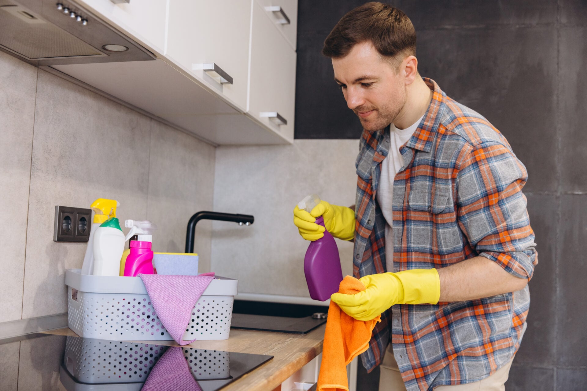 Housekeeper wearing gloves holding cleaning product and rag, ready to clean kitchen counter