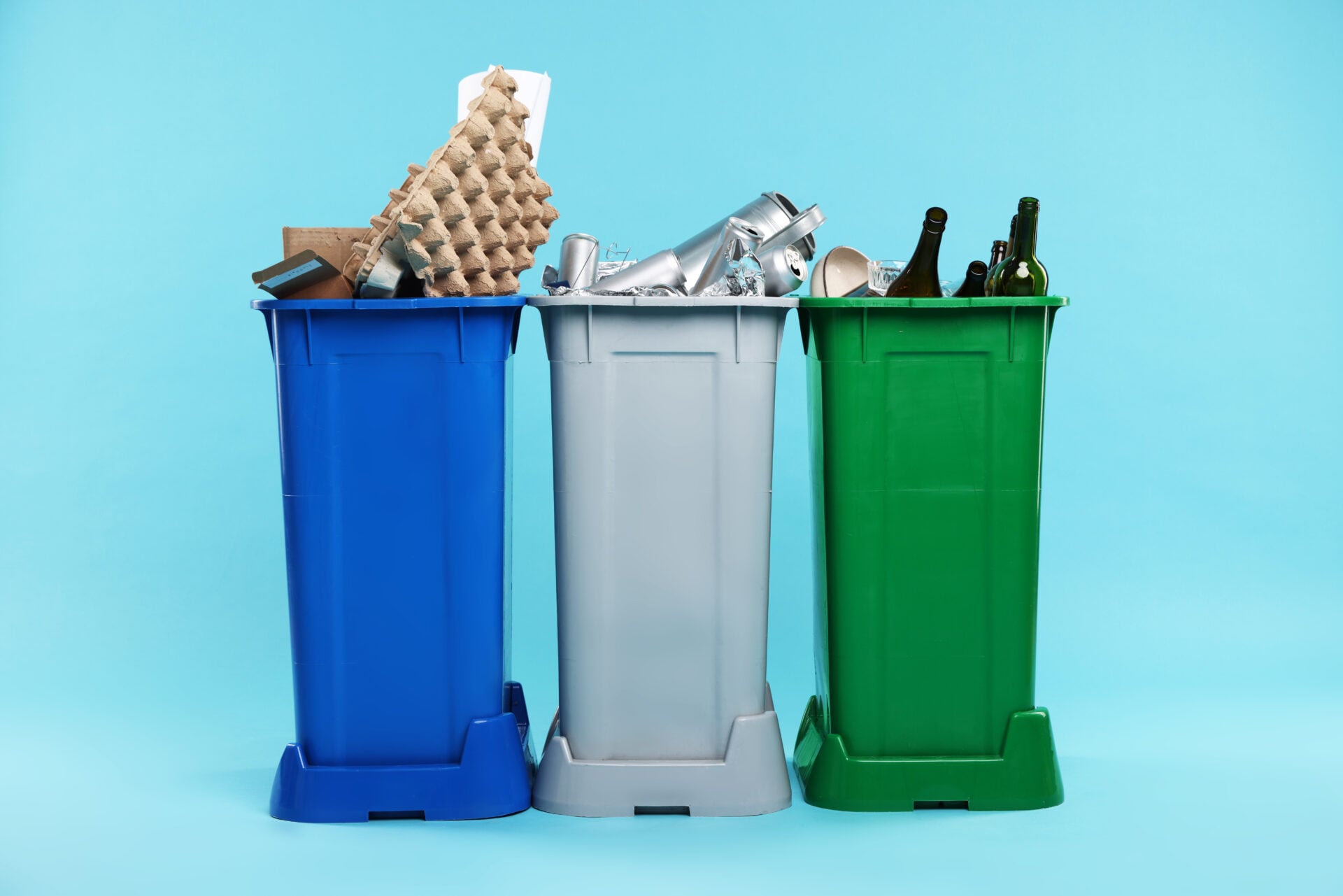 Garbage in trash bins on light blue background. Waste sorting