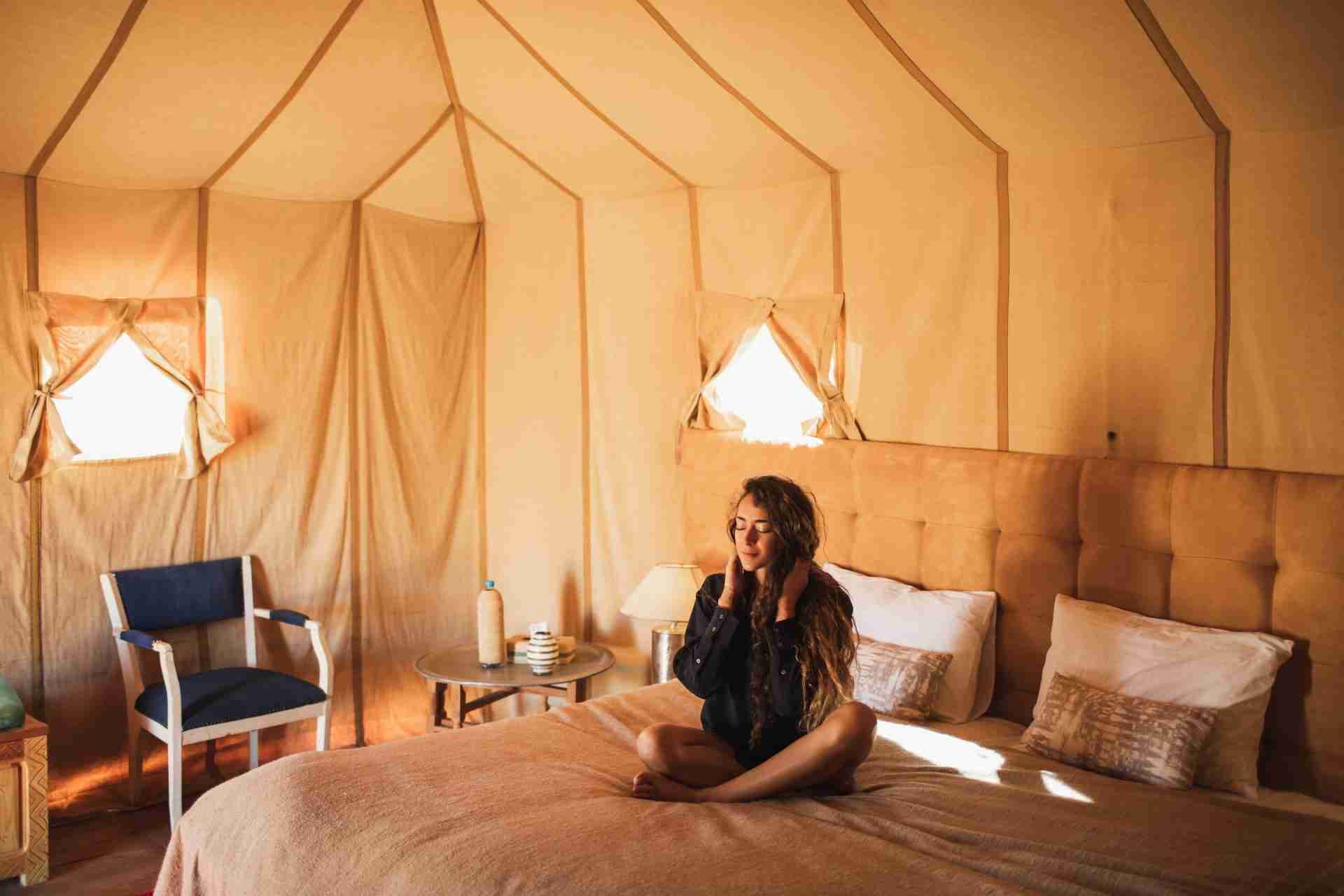 Woman on a bed in a glamping tent