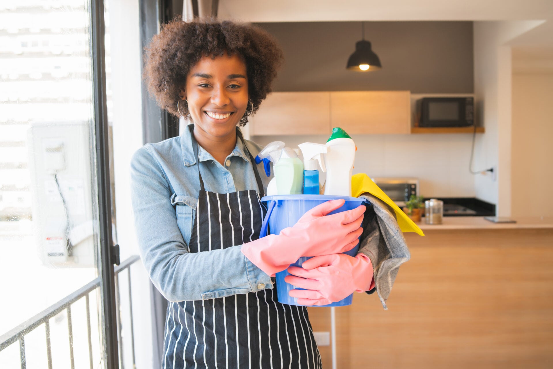 A smiling woman with cleaning supplies