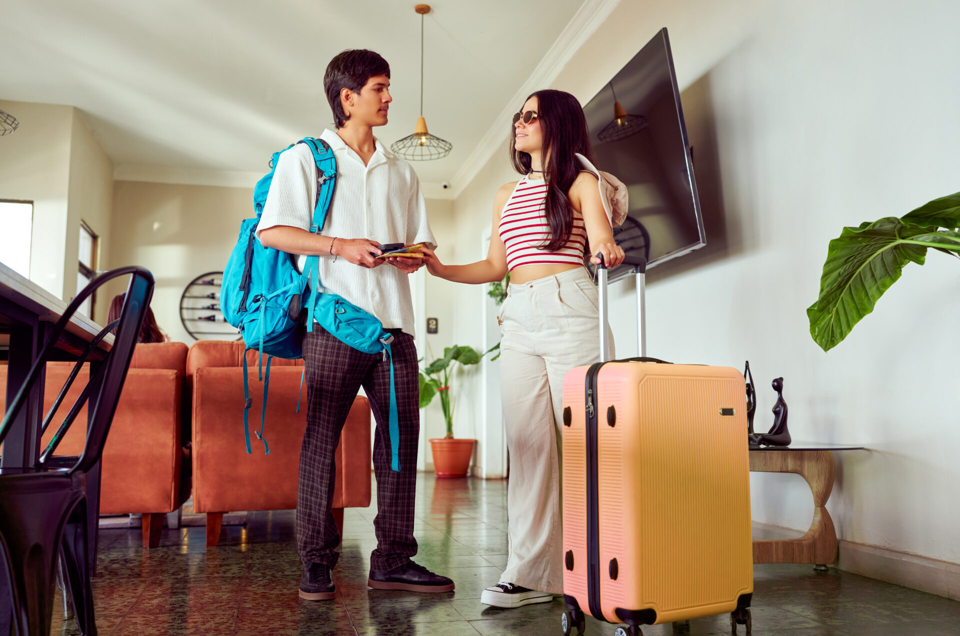 Young latin american couple arriving at hotel lobby handing over passport and credit card to receptionist for check in