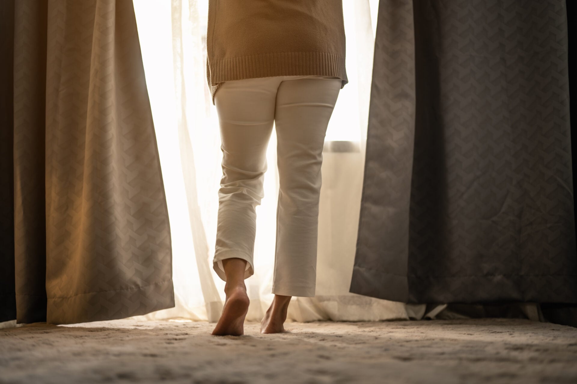 A woman waking up and open the curtains in the morning to get fresh air.