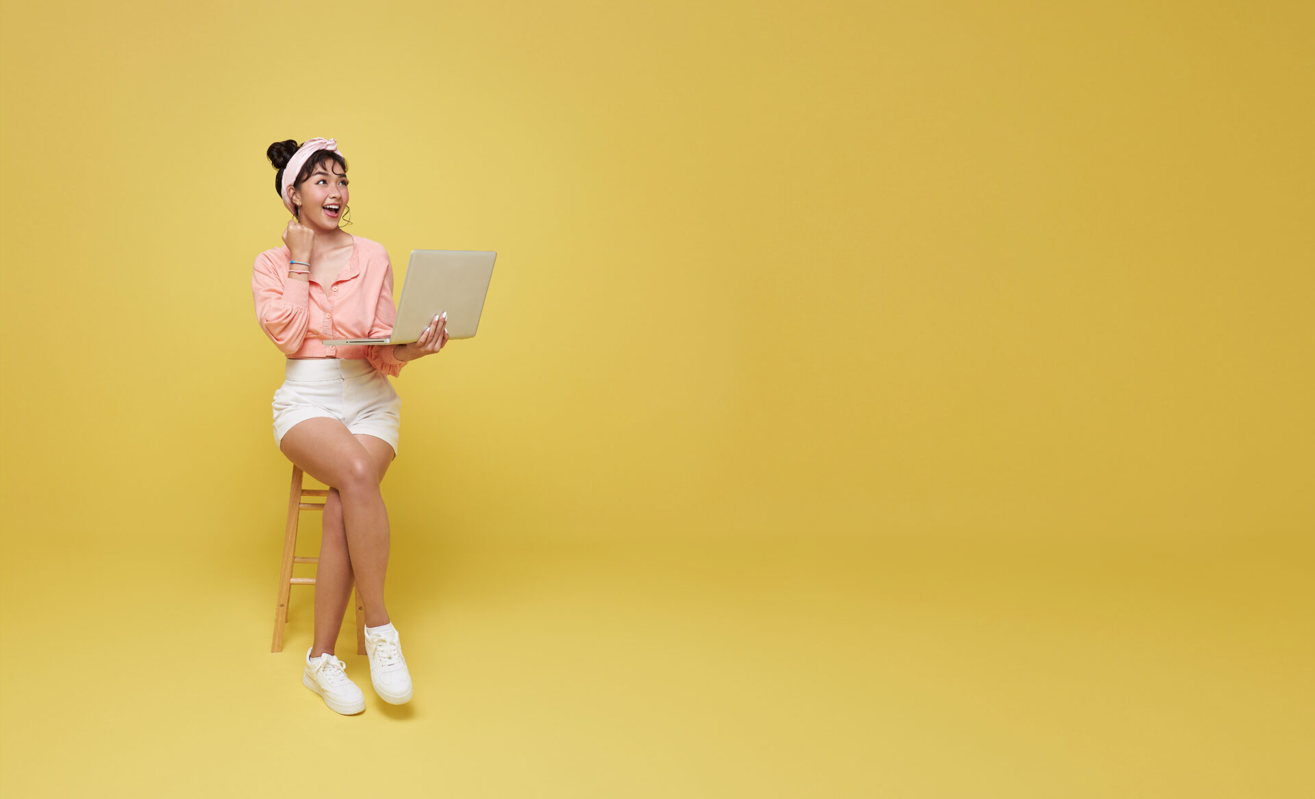 A woman with a laptop and a yellow background